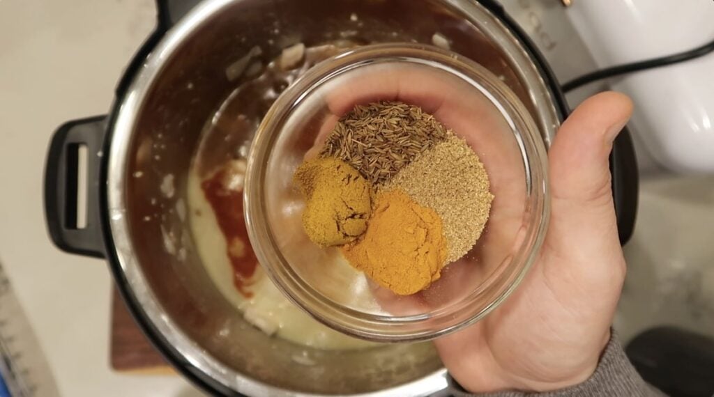 Adding cumin seed, coriander, turmeric, and optional curry powder to pot